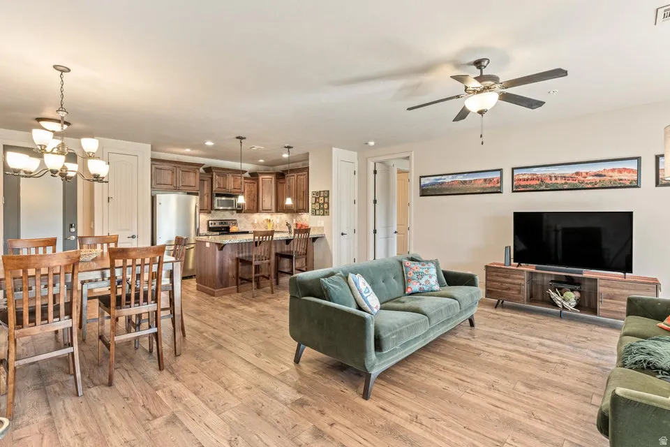 Living room featuring hanging lights, light wood-type flooring, and ceiling fan