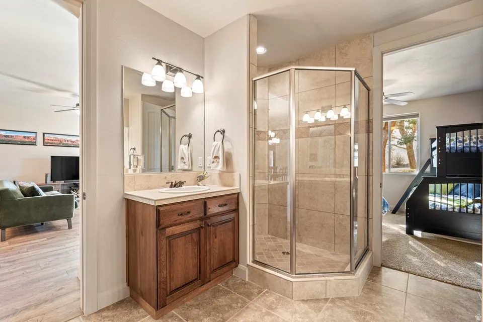 Full bathroom featuring a ceiling fan, vanity, a shower stall, and connected bathroom