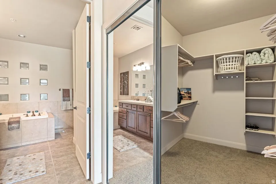 Walk in closet with light carpet and light tile patterned floors