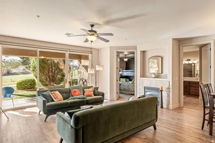 Living room featuring wood-type flooring, a tile fireplace, and a ceiling fan