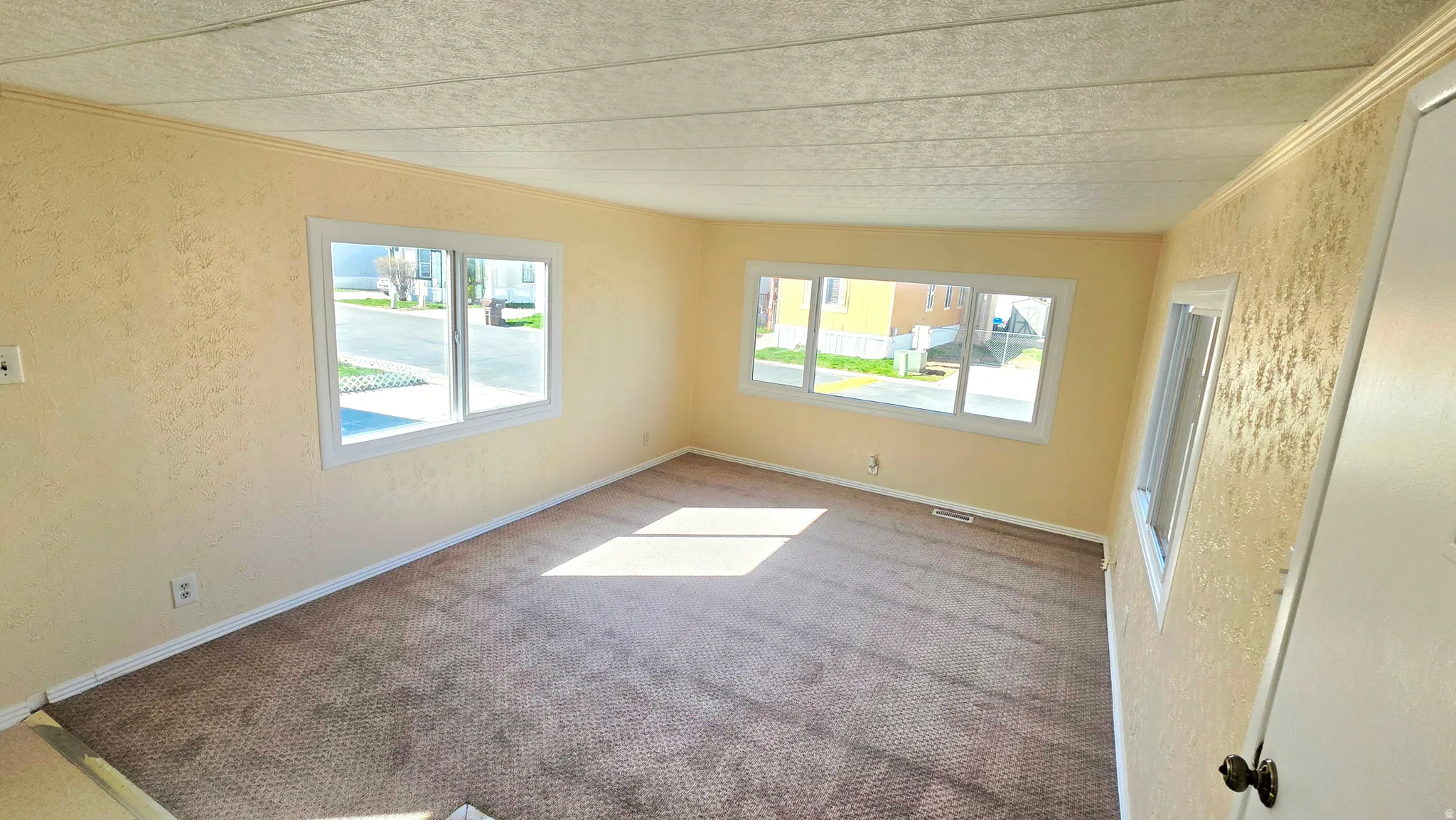 Carpeted spare room with a textured wall and ornamental molding