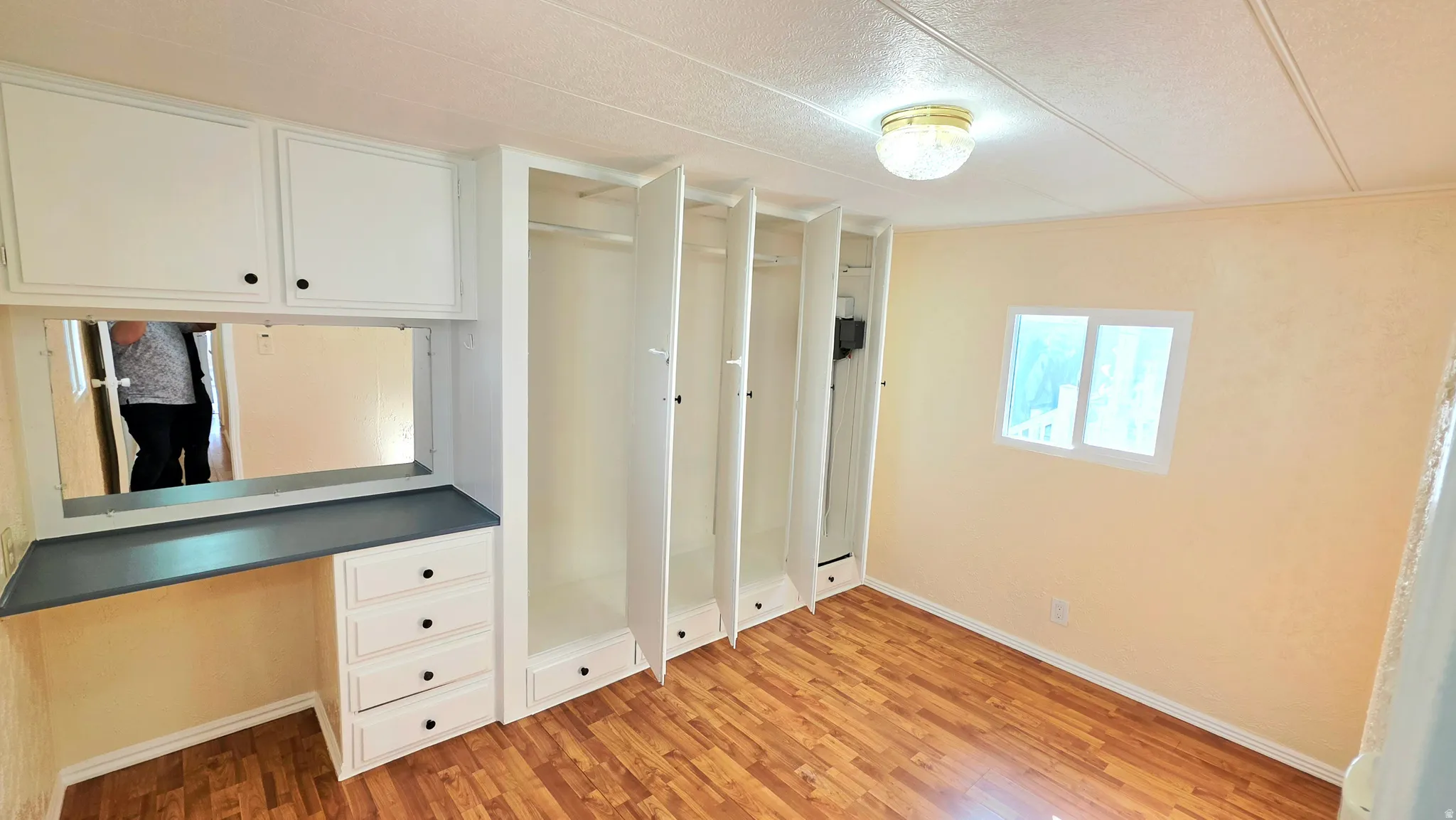 Unfurnished bedroom featuring built in study area, light wood finished floors, and multiple closets
