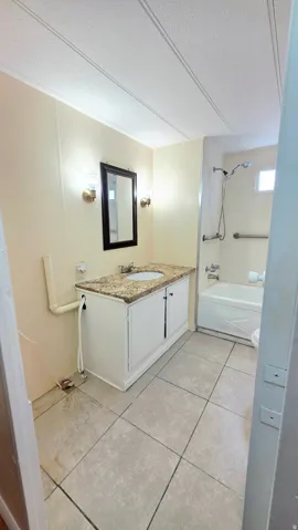 Full bathroom featuring vanity, a textured ceiling, light tile patterned floors, and washtub / shower combination