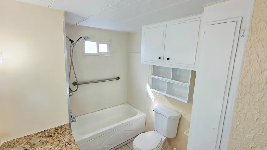 Full bathroom featuring tub / shower combination and a textured ceiling