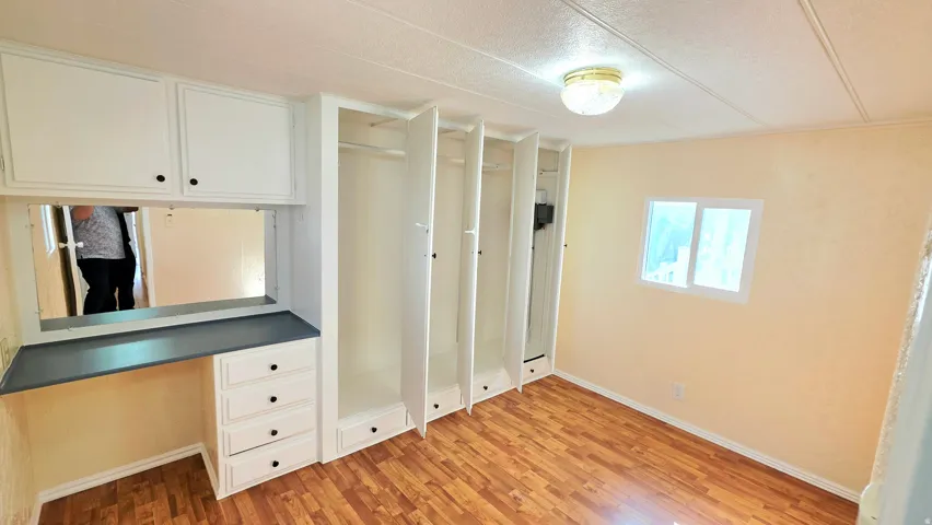 Unfurnished bedroom featuring built in study area, light wood finished floors, and multiple closets