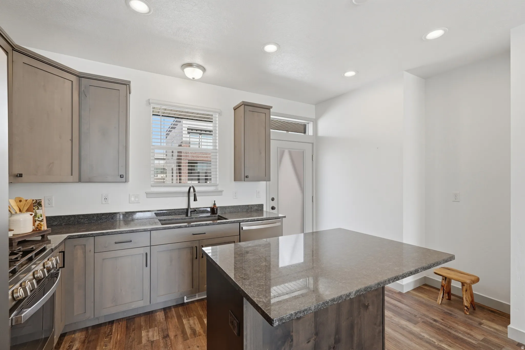 Kitchen featuring dark stone counters, stainless steel appliances, dark wood-type flooring, a kitchen island, and recessed lighting