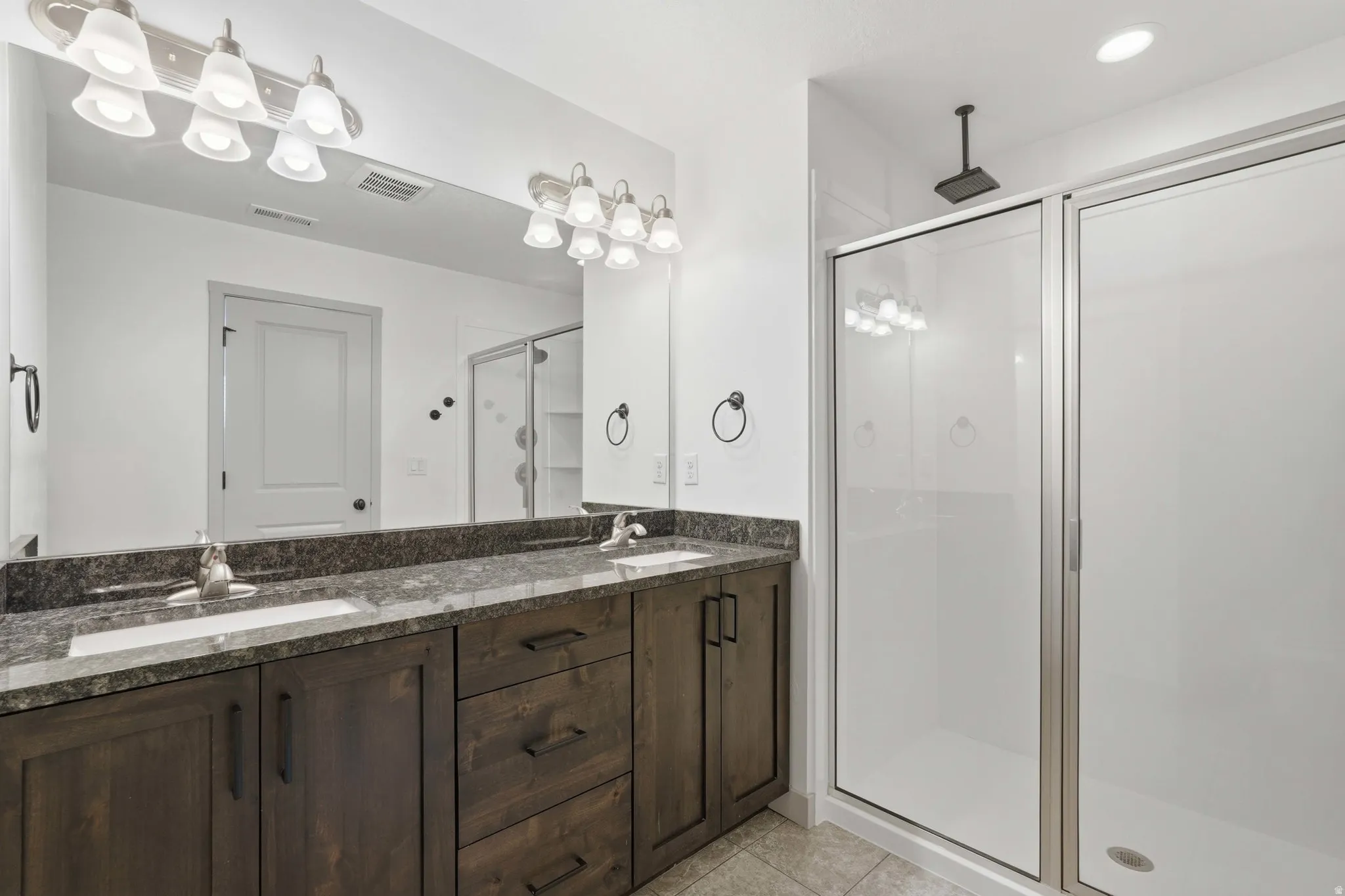 Primary Bathroom featuring double vanity, a shower stall, and light tile patterned floors