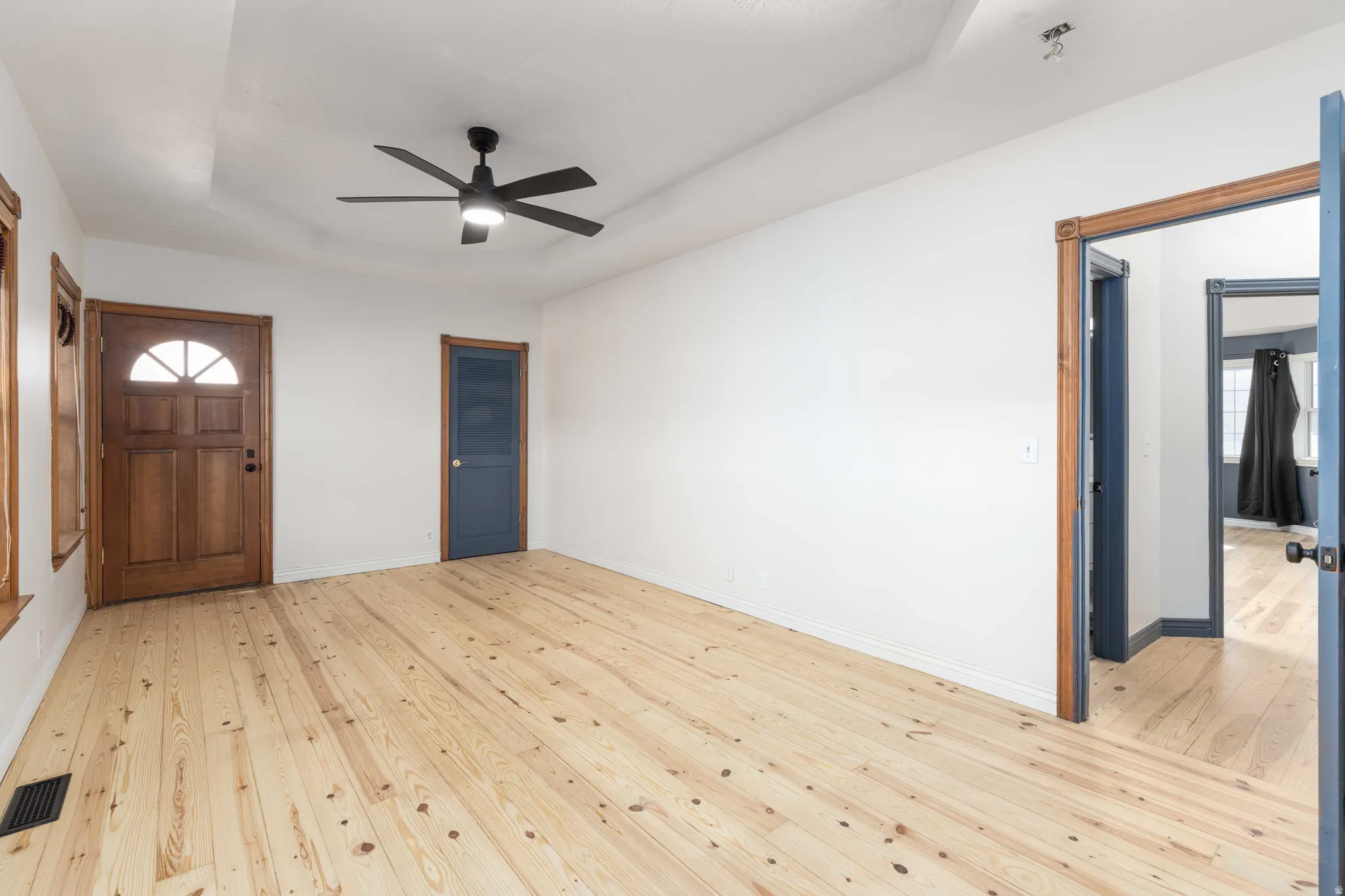 Front room featuring a tray ceiling, light wood finished floors, and ceiling fan. Could be used as Bedroom or office.