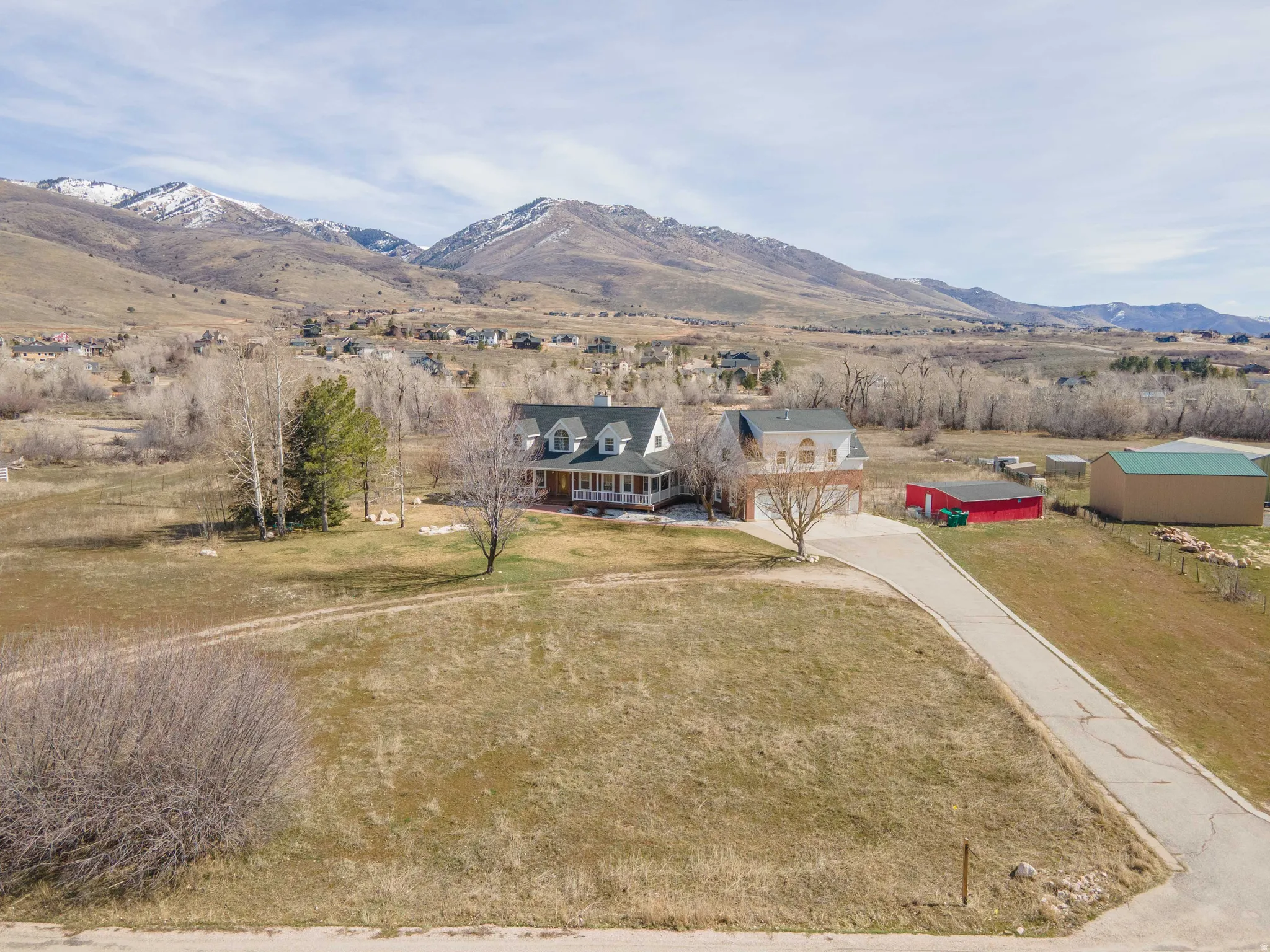 View of front of house with concrete driveway, a mountain view, a rural view, and a front yard