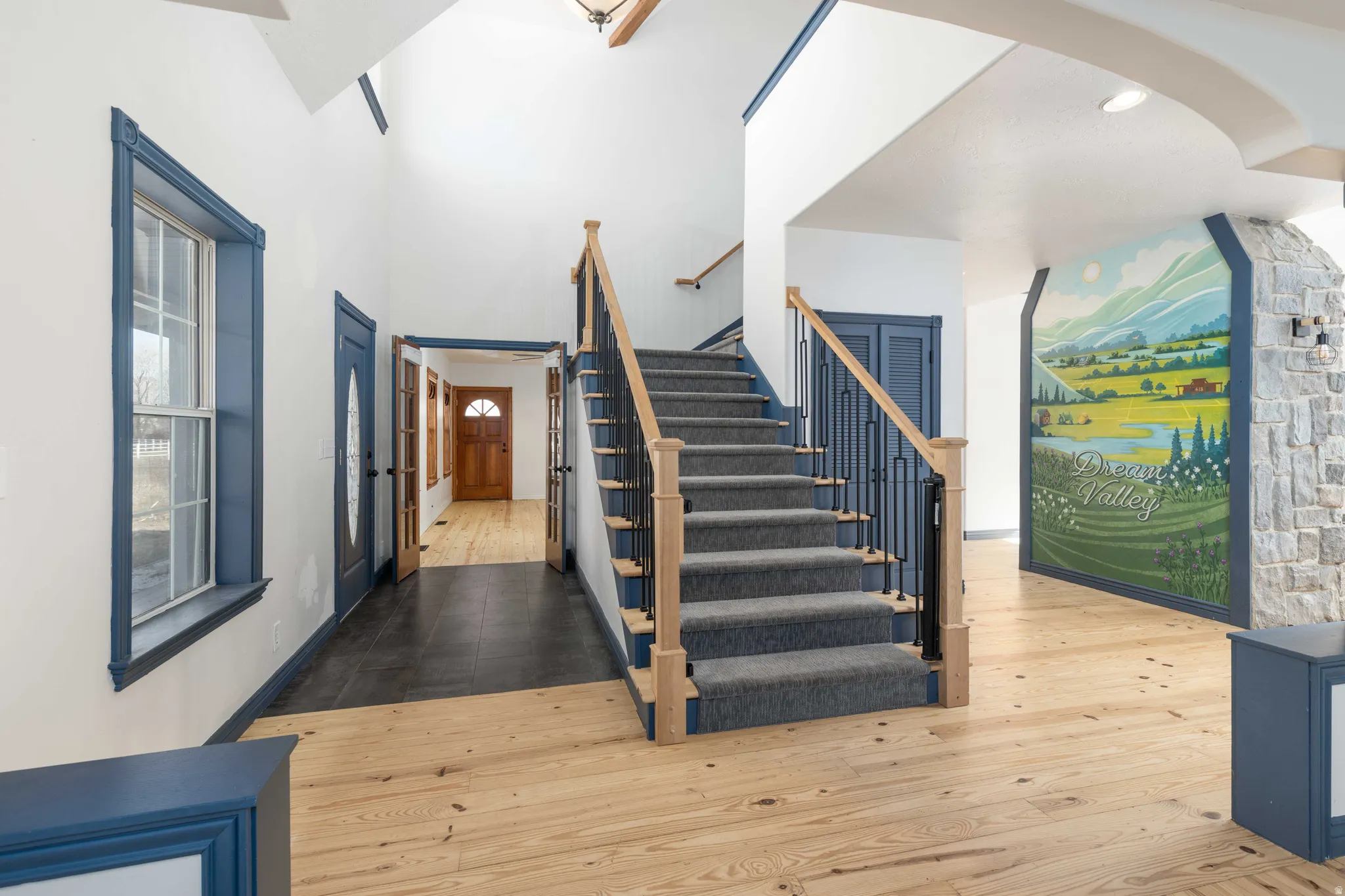 Stairway with wood-type flooring, arched walkways, and a high ceiling
