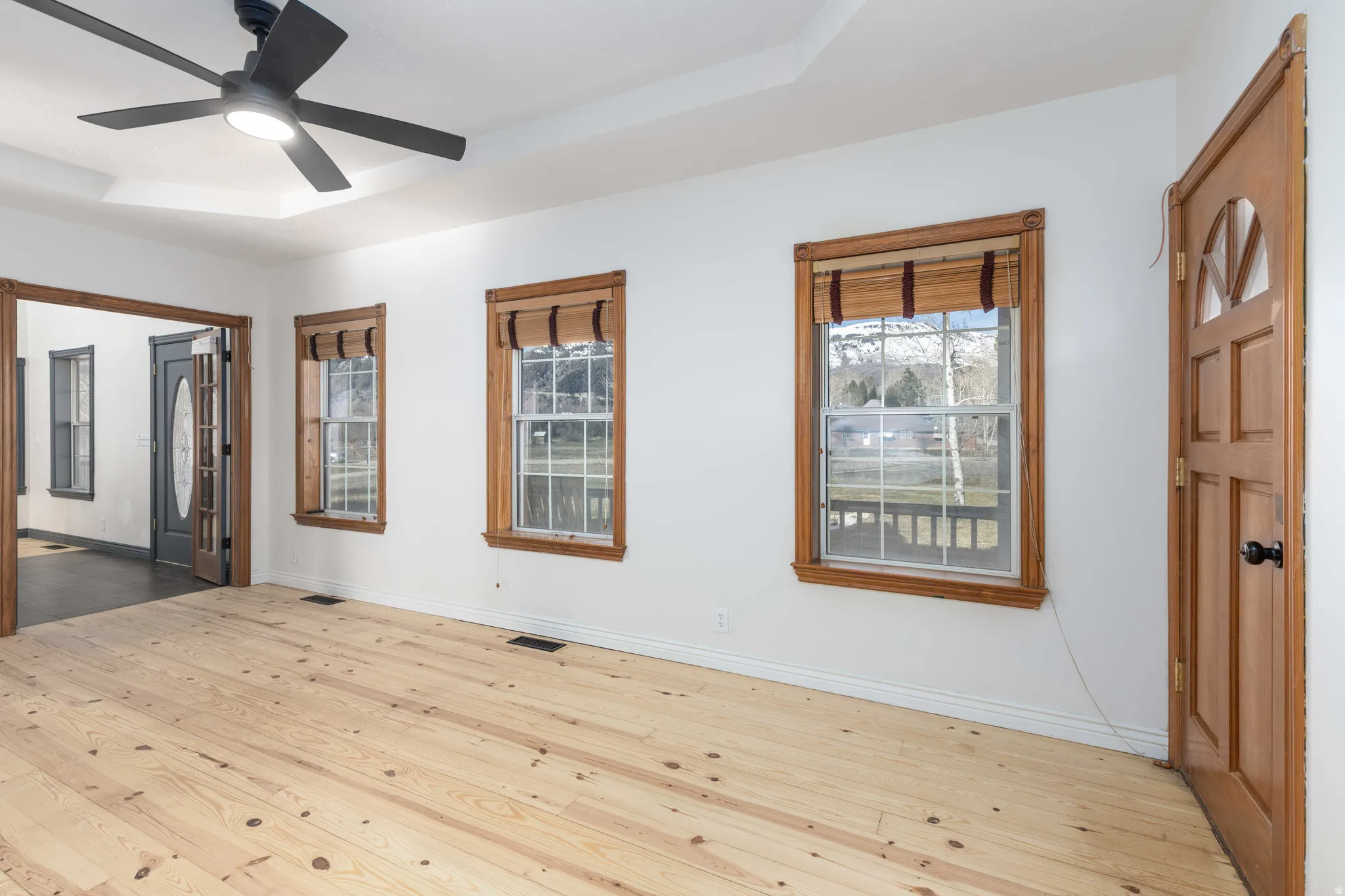 Front room featuring a tray ceiling, light wood finished floors, and ceiling fan. Could be used as Bedroom or office.