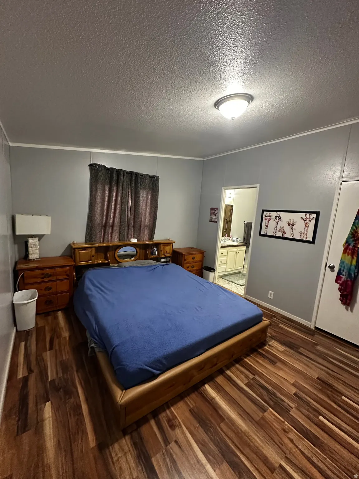Bedroom with dark wood-style floors, a textured ceiling, crown molding, and ensuite bathroom
