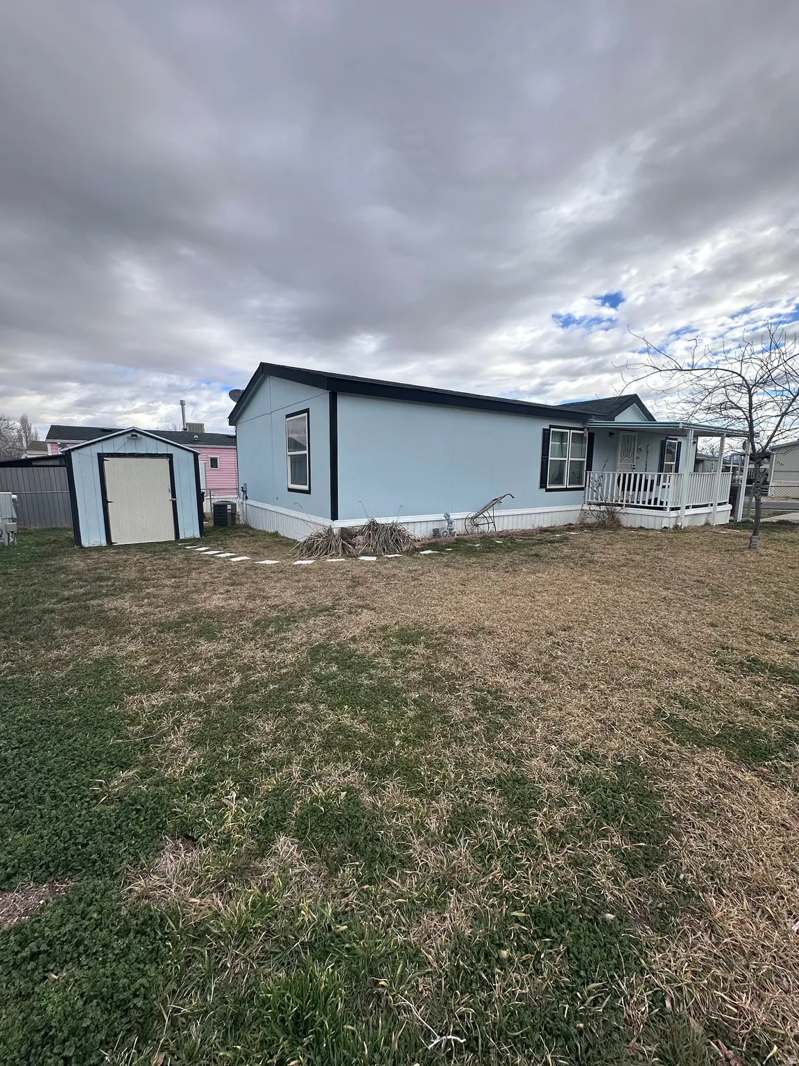 View of front of home featuring a storage shed, a front yard, and covered porch