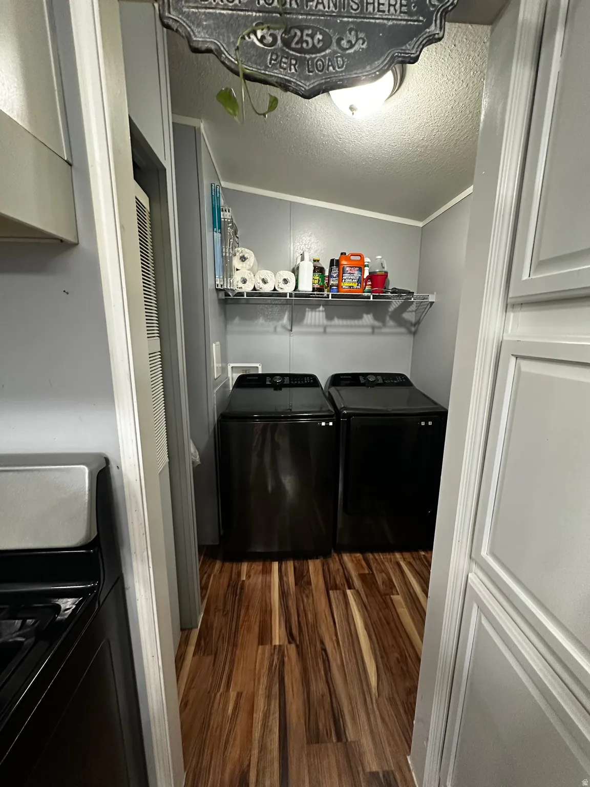 Laundry room with a textured ceiling, dark wood-type flooring, and washer and clothes dryer