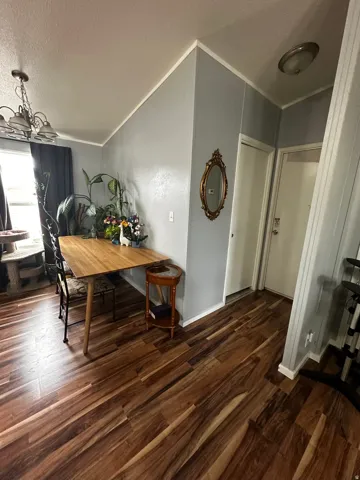 Dining space featuring dark wood-style floors, suspended lighting, and ornamental molding