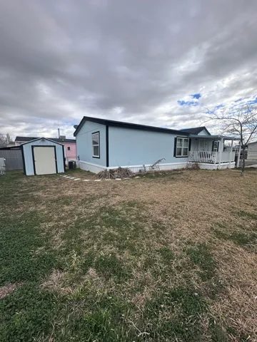View of front of home featuring a storage shed, a front yard, and covered porch