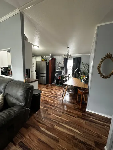 Living room featuring a textured ceiling, suspended lighting, and dark wood-style floors