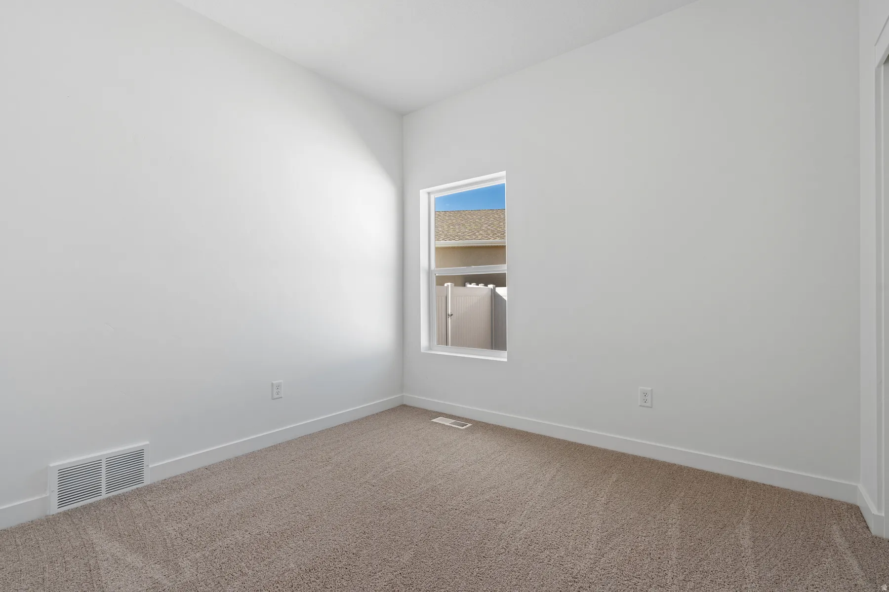 Carpeted spare room featuring baseboards