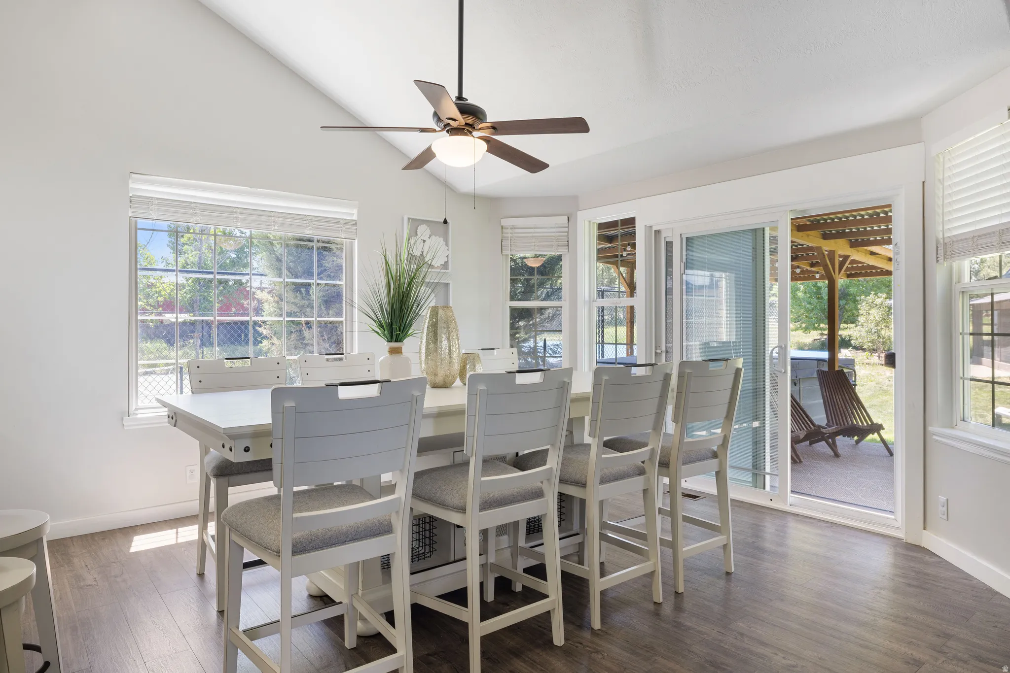 Dining space featuring dark wood-style flooring, a ceiling fan, and vaulted ceiling
