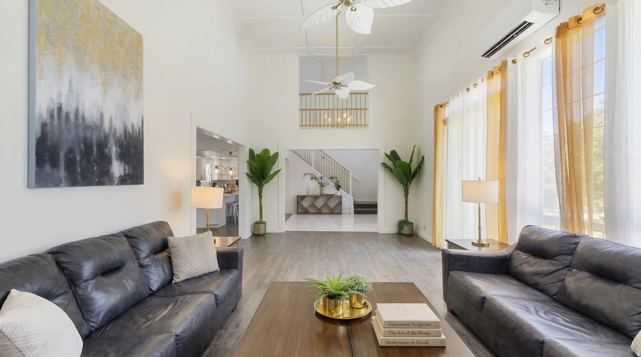 Living area featuring wood finished floors, ceiling fan, a high ceiling, and crown molding