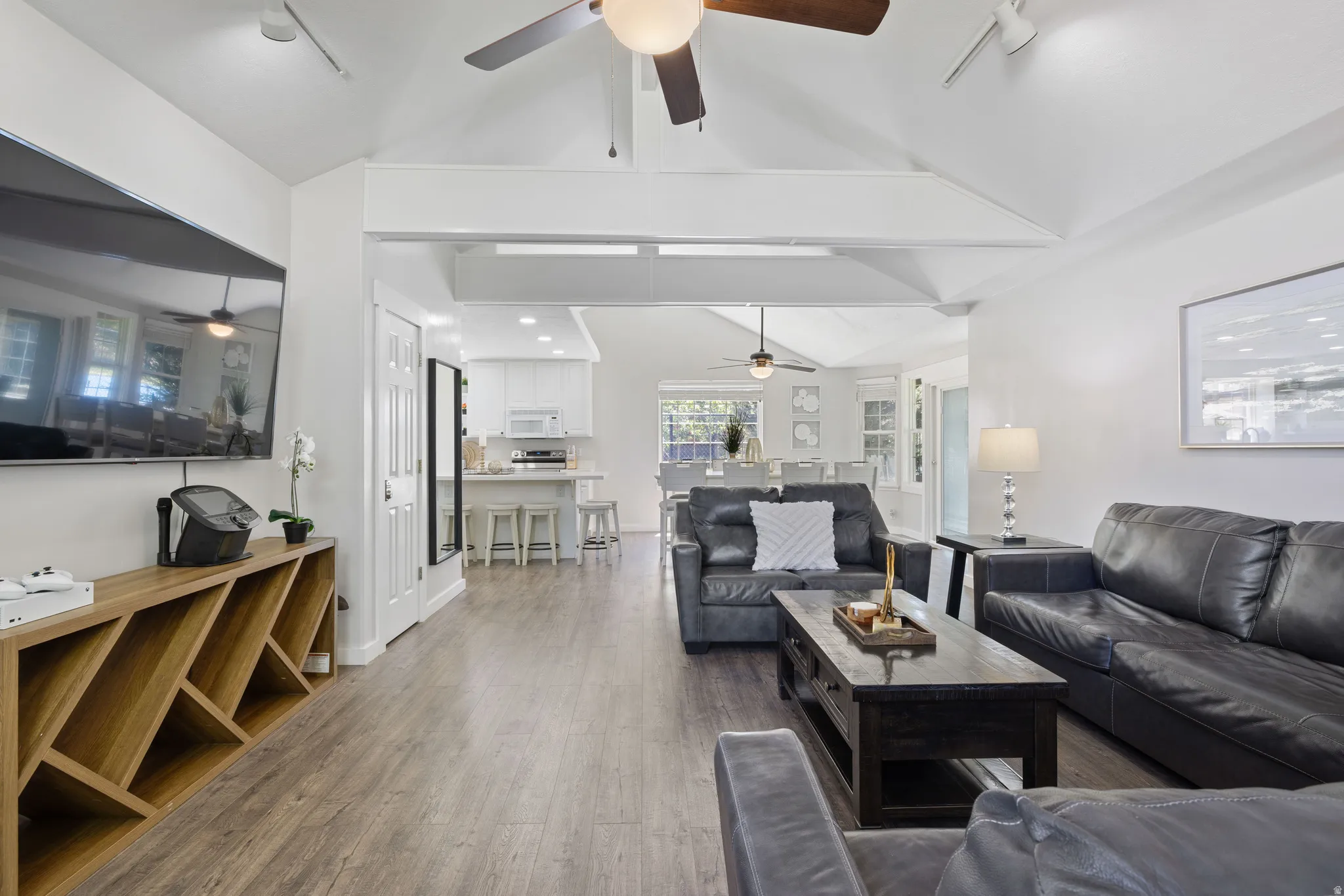 Living area with rail lighting, dark wood finished floors, and vaulted ceiling