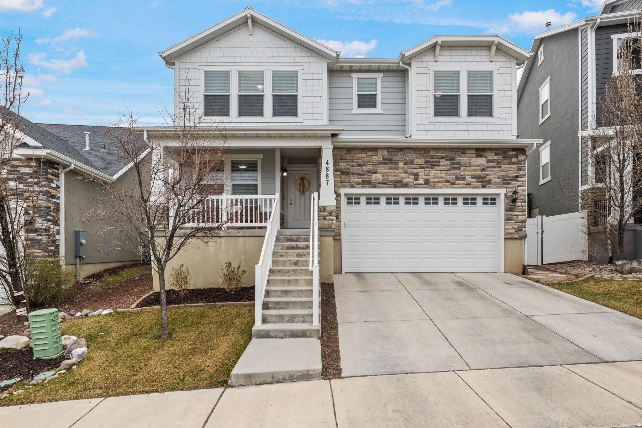 View of front of house with a porch, concrete driveway, stone siding, and an attached garage