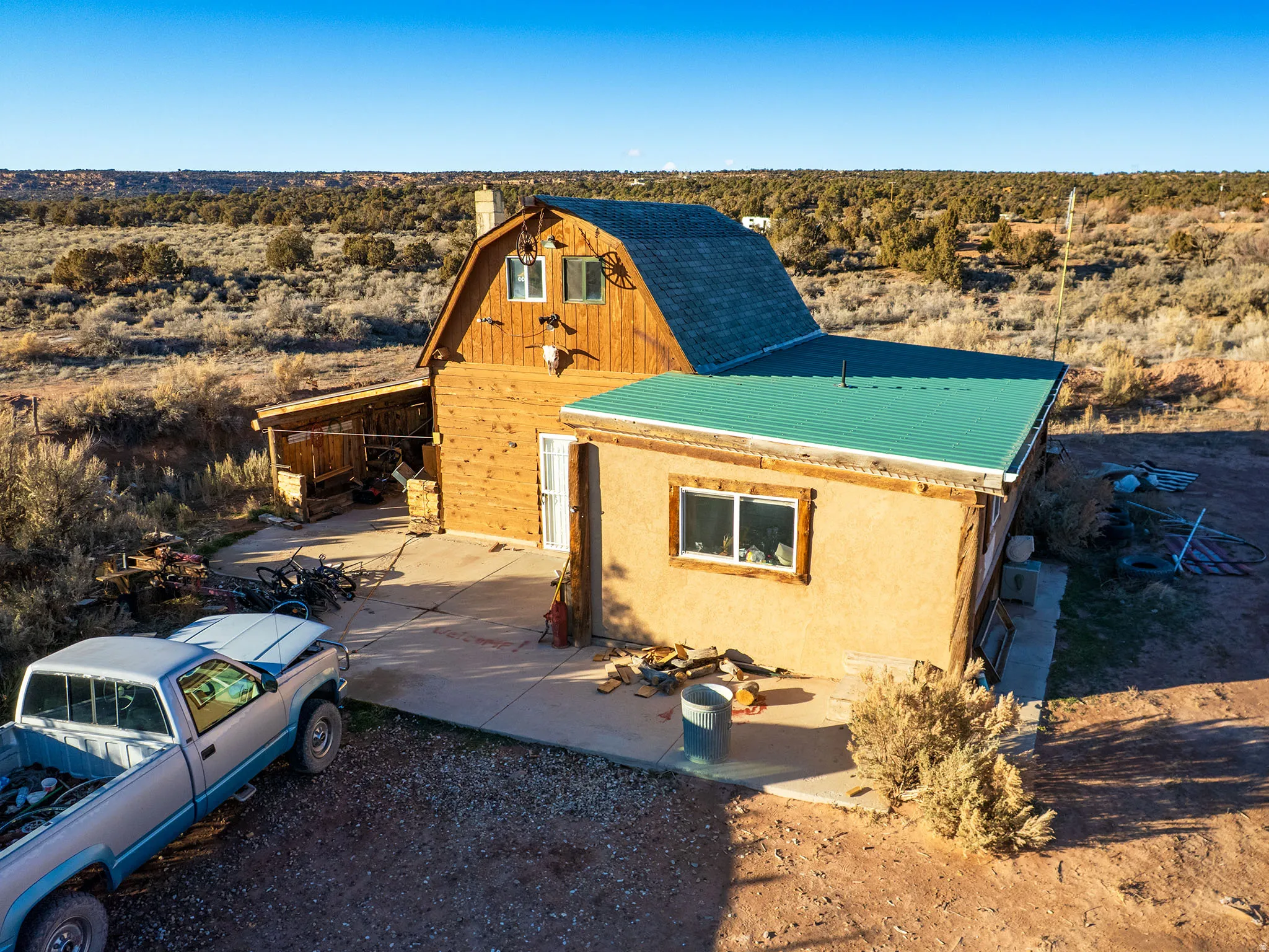 View of front facade featuring view of desert landscape, stucco siding, a chimney, a metal roof, and a view of rural / pastoral area