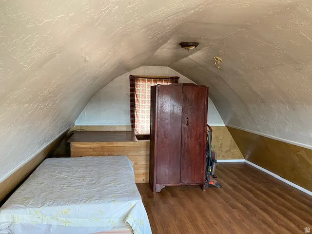 Bedroom featuring dark wood-style flooring, a textured wall, and a textured ceiling