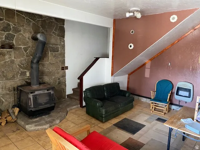 Living area featuring heating unit, a wood stove, and light tile patterned floors