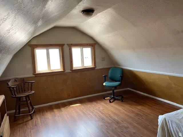 Additional living space featuring a textured ceiling and wood finished floors