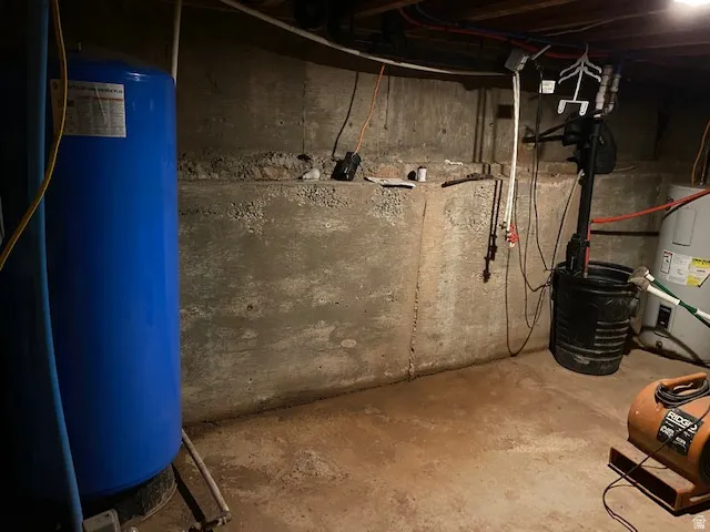 Unfinished below grade area with a water pressure tank and water heater