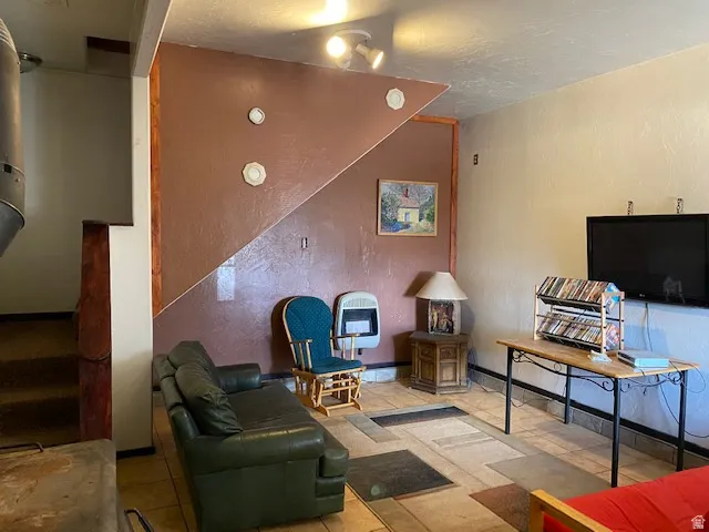 Sitting room with a textured wall, heating unit, a textured ceiling, and light tile patterned floors
