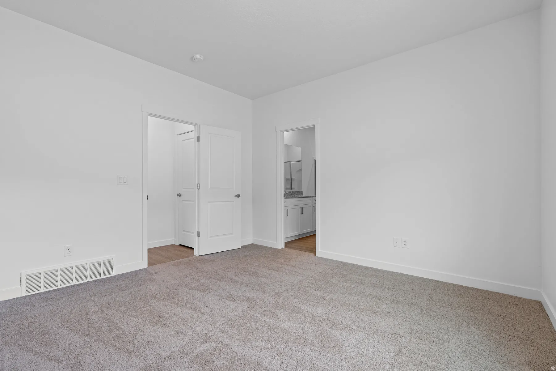 Unfurnished bedroom featuring light colored carpet and ensuite bath