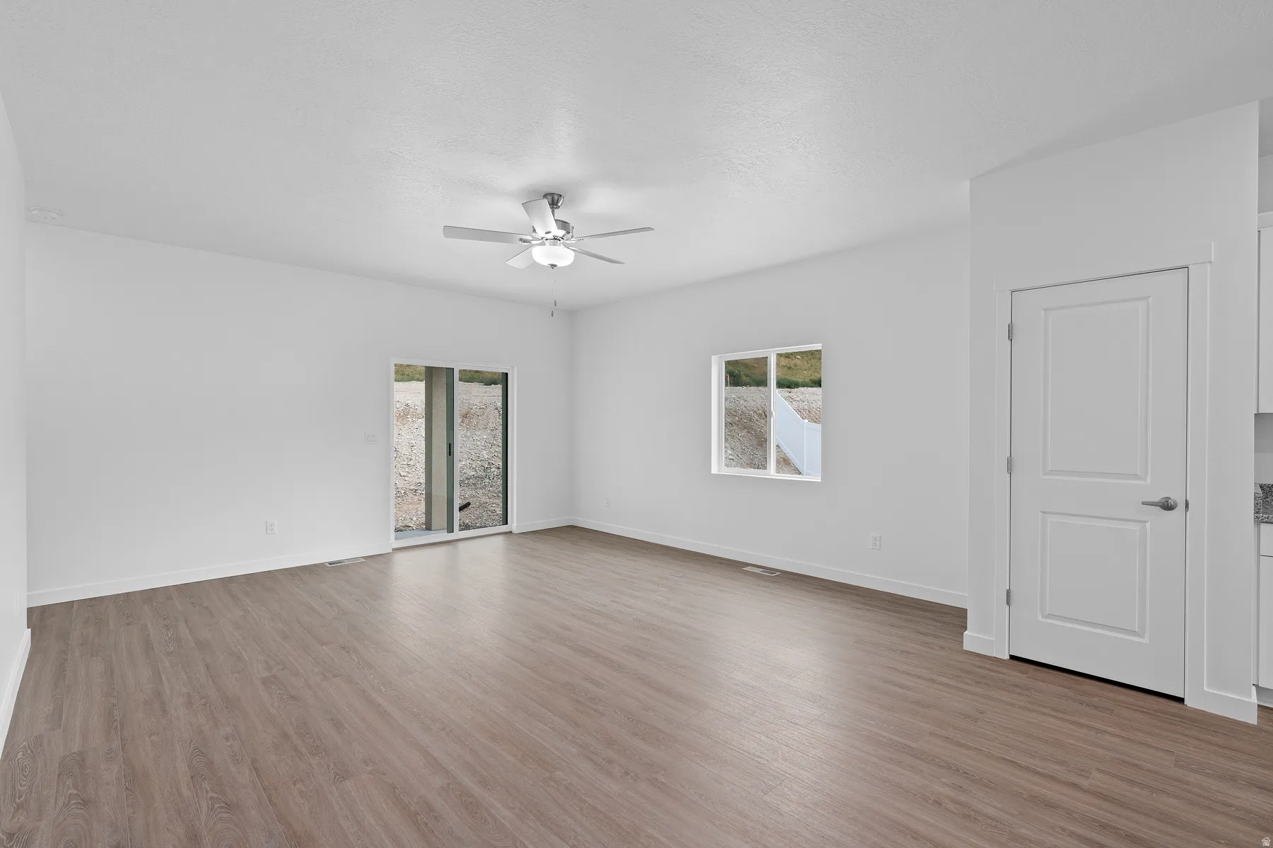 Spare room with light wood-style flooring, plenty of natural light, and ceiling fan