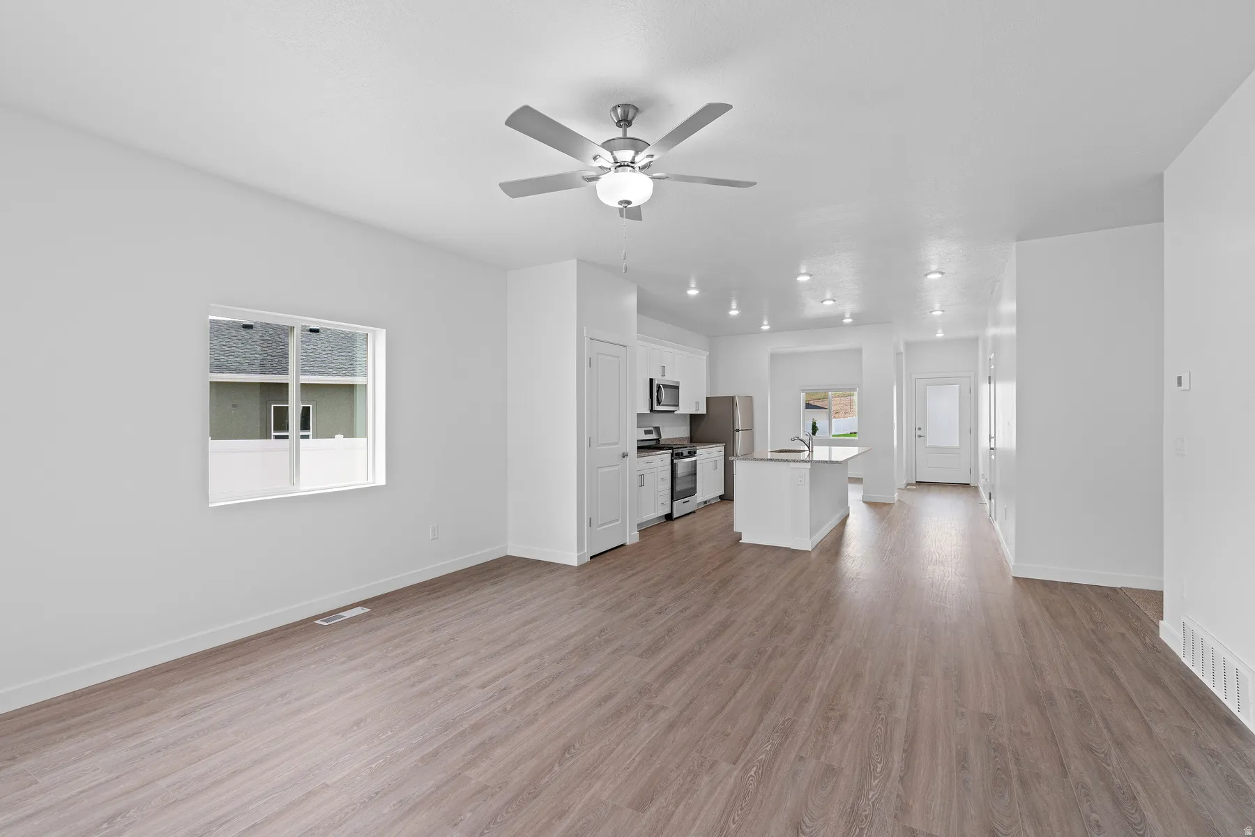 Unfurnished living room featuring light wood-style flooring and ceiling fan