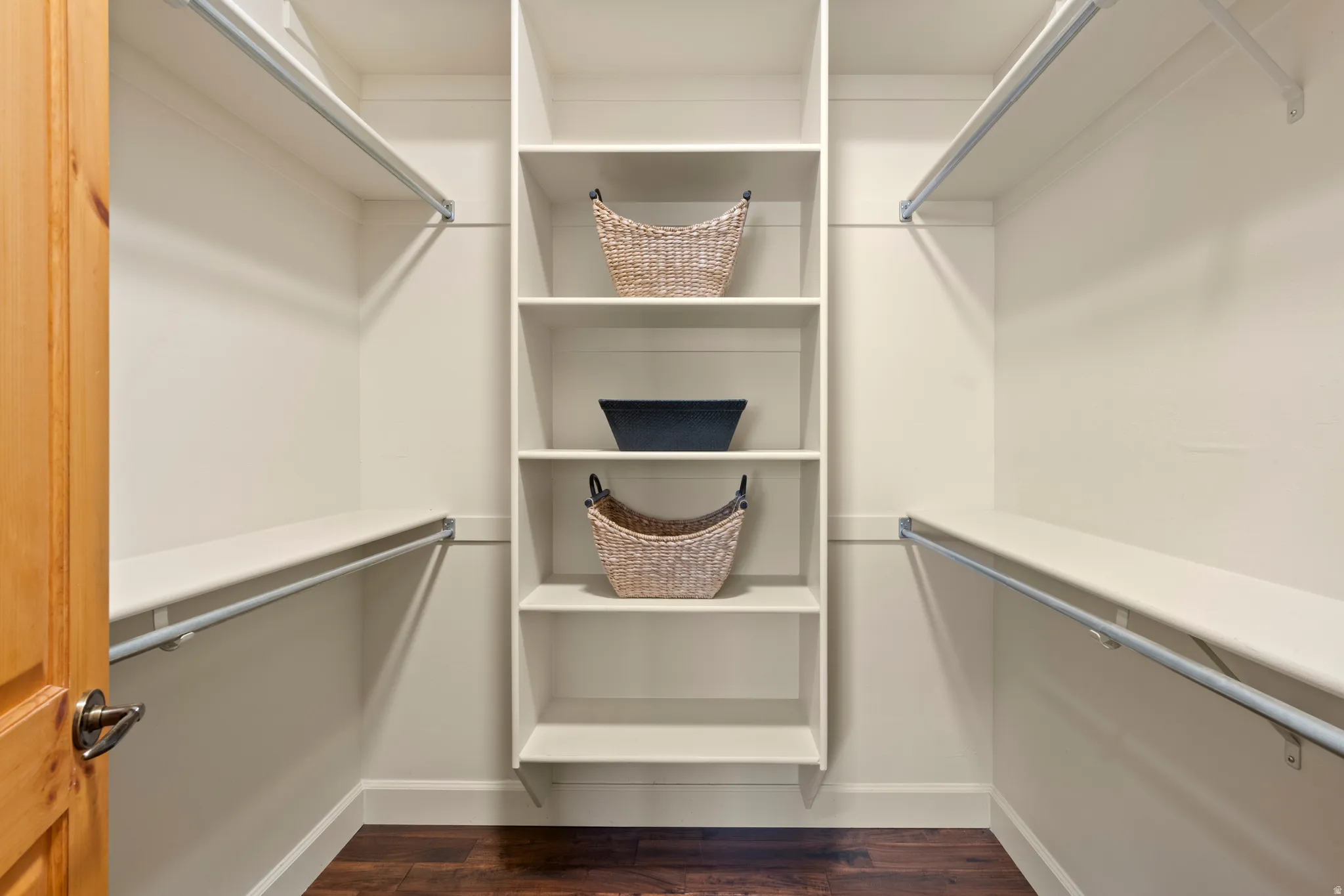 Walk in closet with dark wood-style flooring