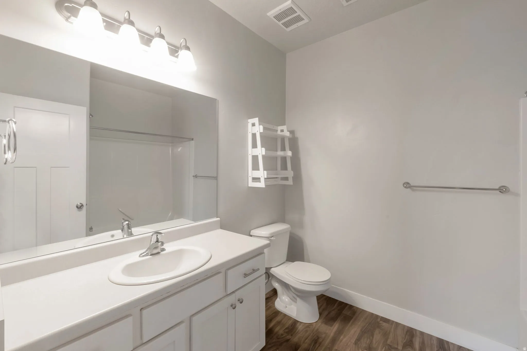 Bathroom featuring a white vanity with an integrated sink, polished chrome faucet, and overhead bar lighting