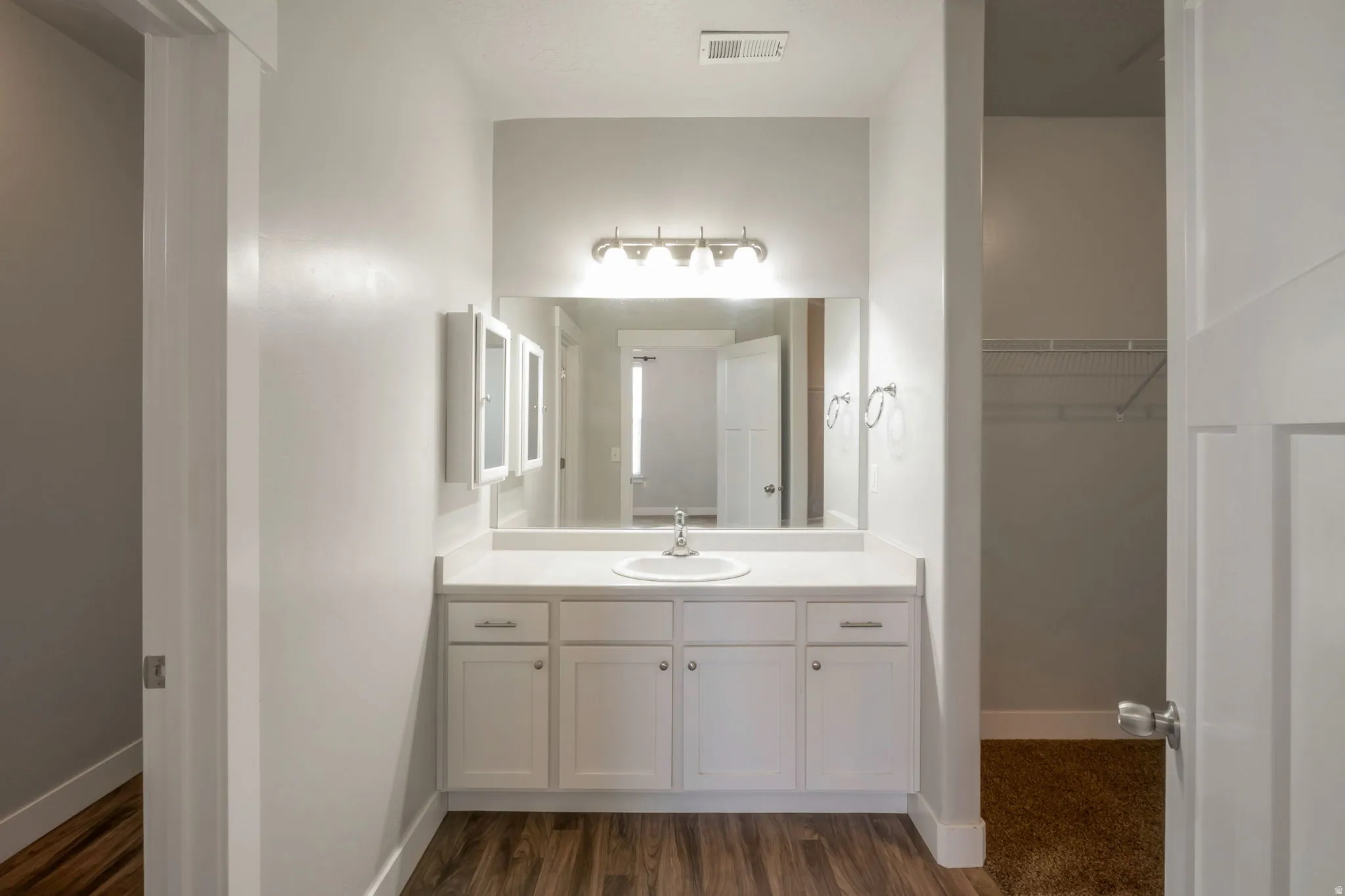 Bathroom vanity with a white countertop, under-mount sink, and dual medicine cabinets