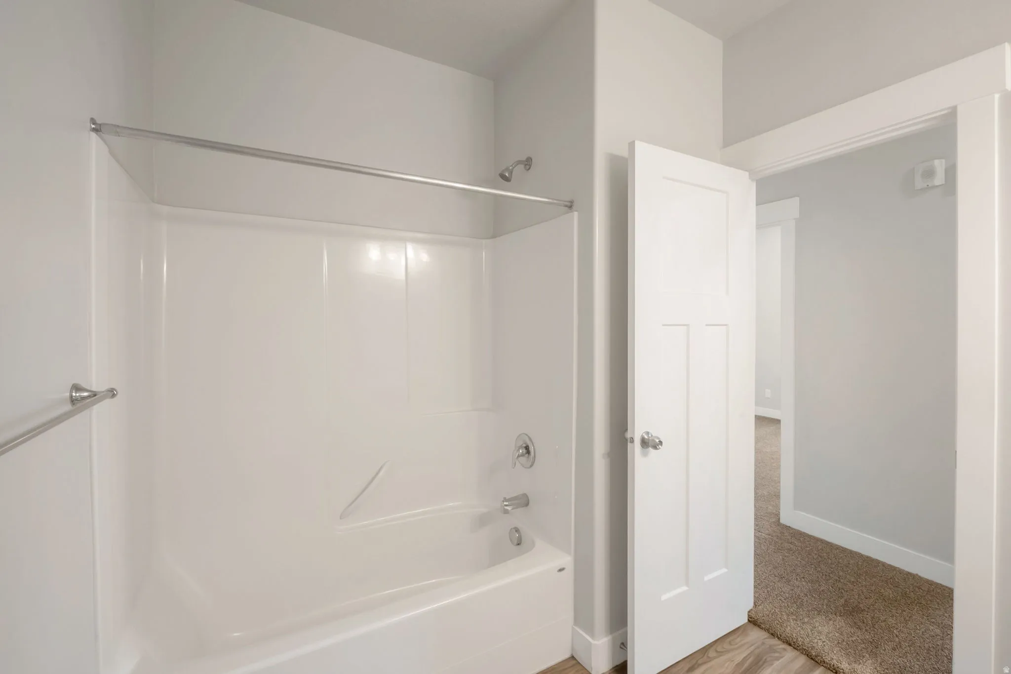 White fiberglass tub and shower combination with a chrome shower head and faucet