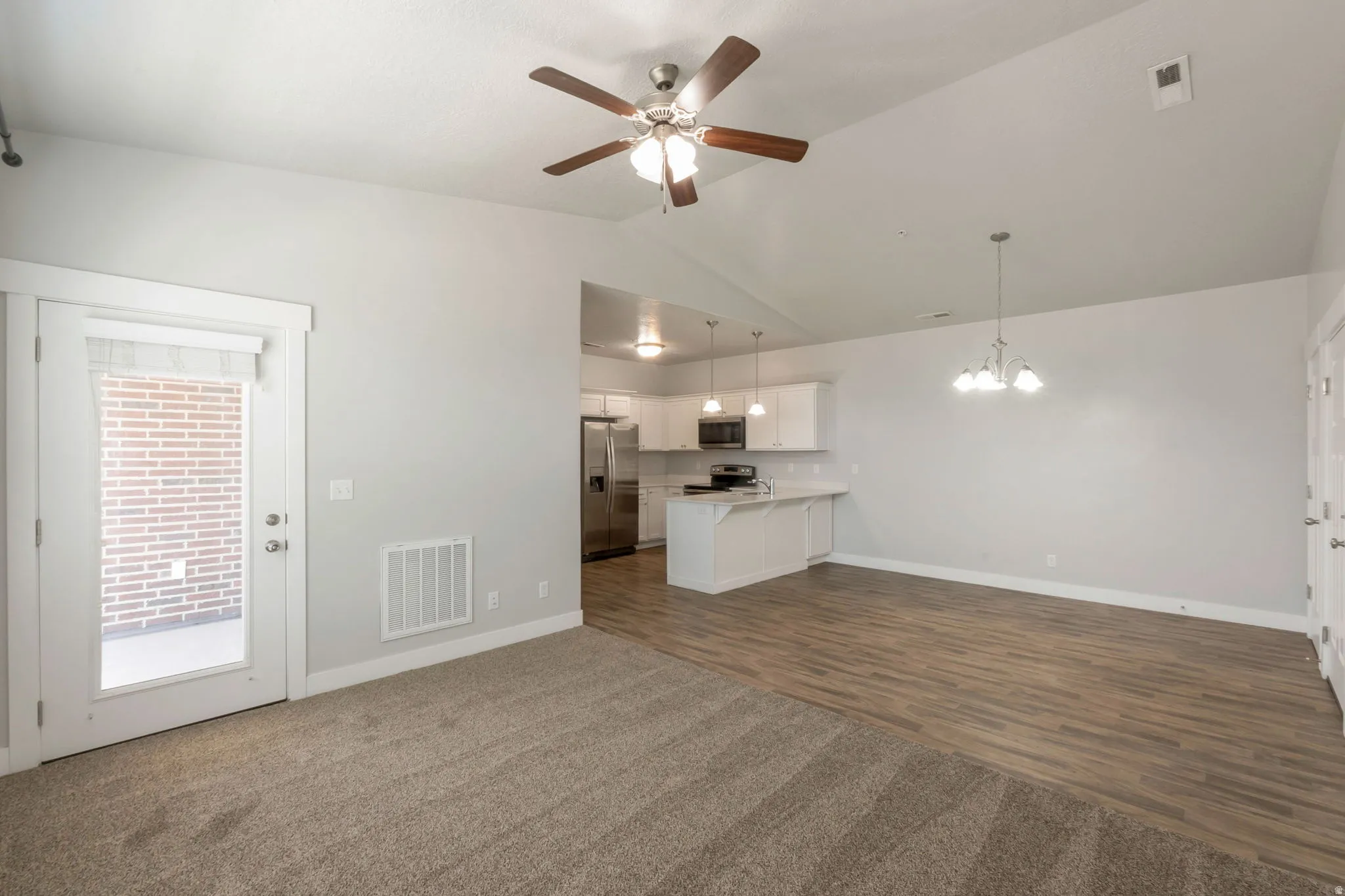Open-concept living area featuring a vaulted ceiling and an integrated ceiling fan