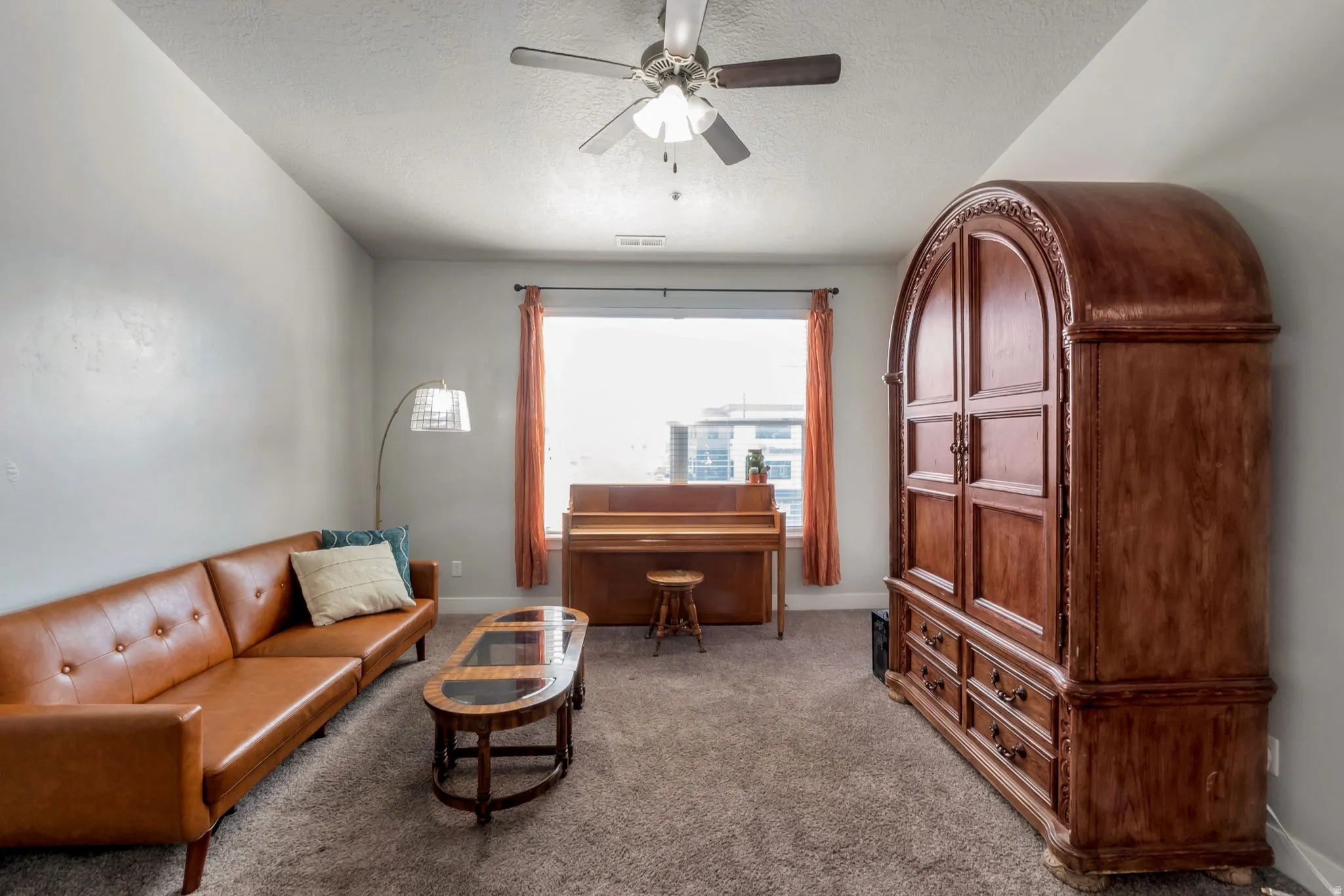 Sitting room with carpet flooring, a ceiling fan, and a textured ceiling