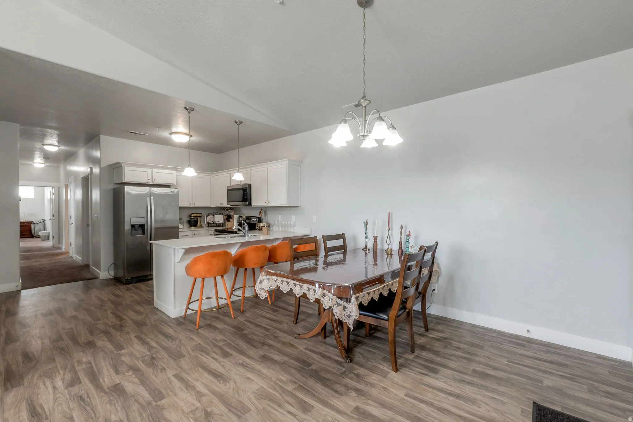 Dining space with lofted ceiling, suspended lighting, and light wood-style flooring