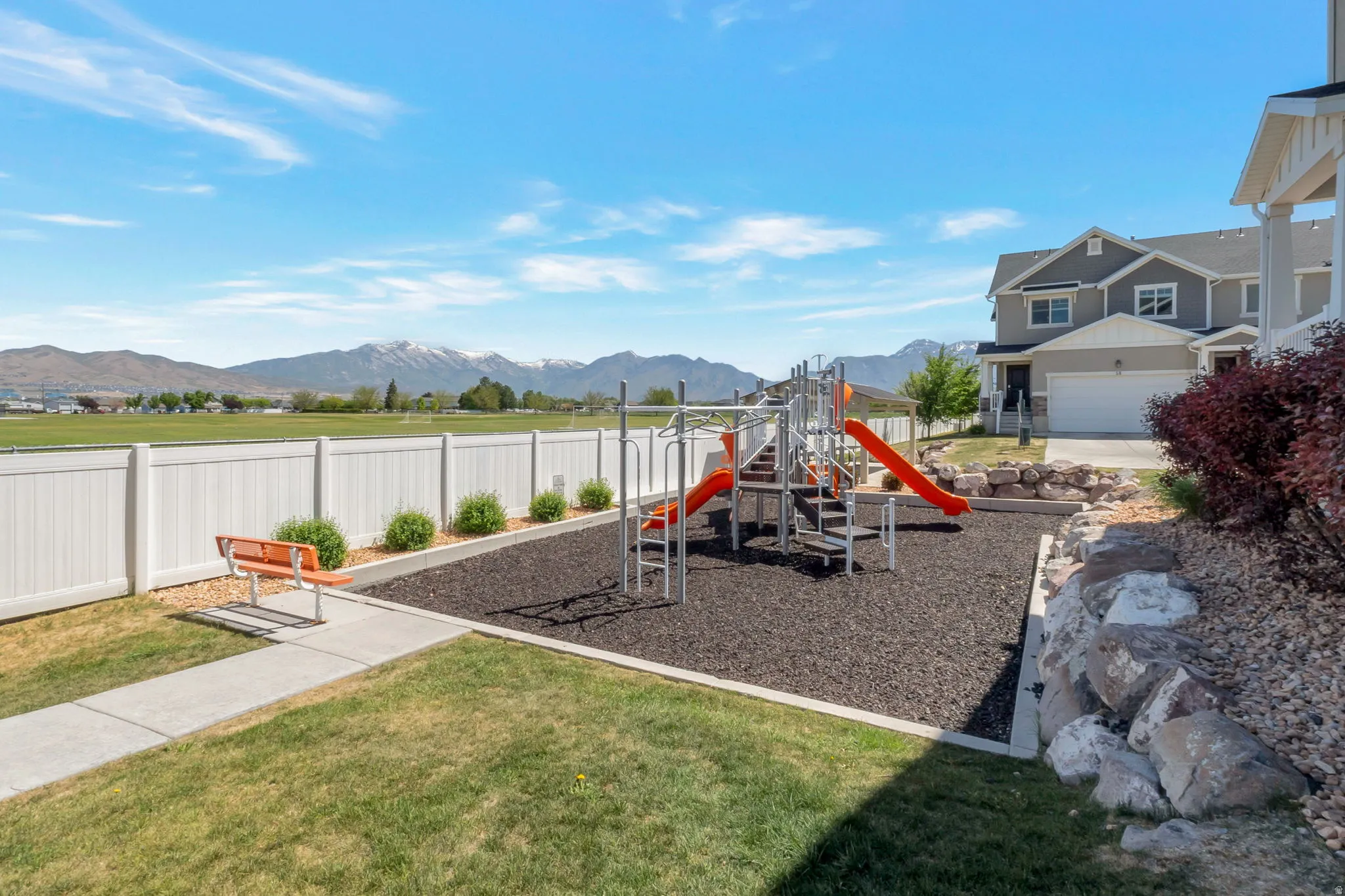 Outdoor playground featuring rubberized surfacing, two slides, and climbing structures