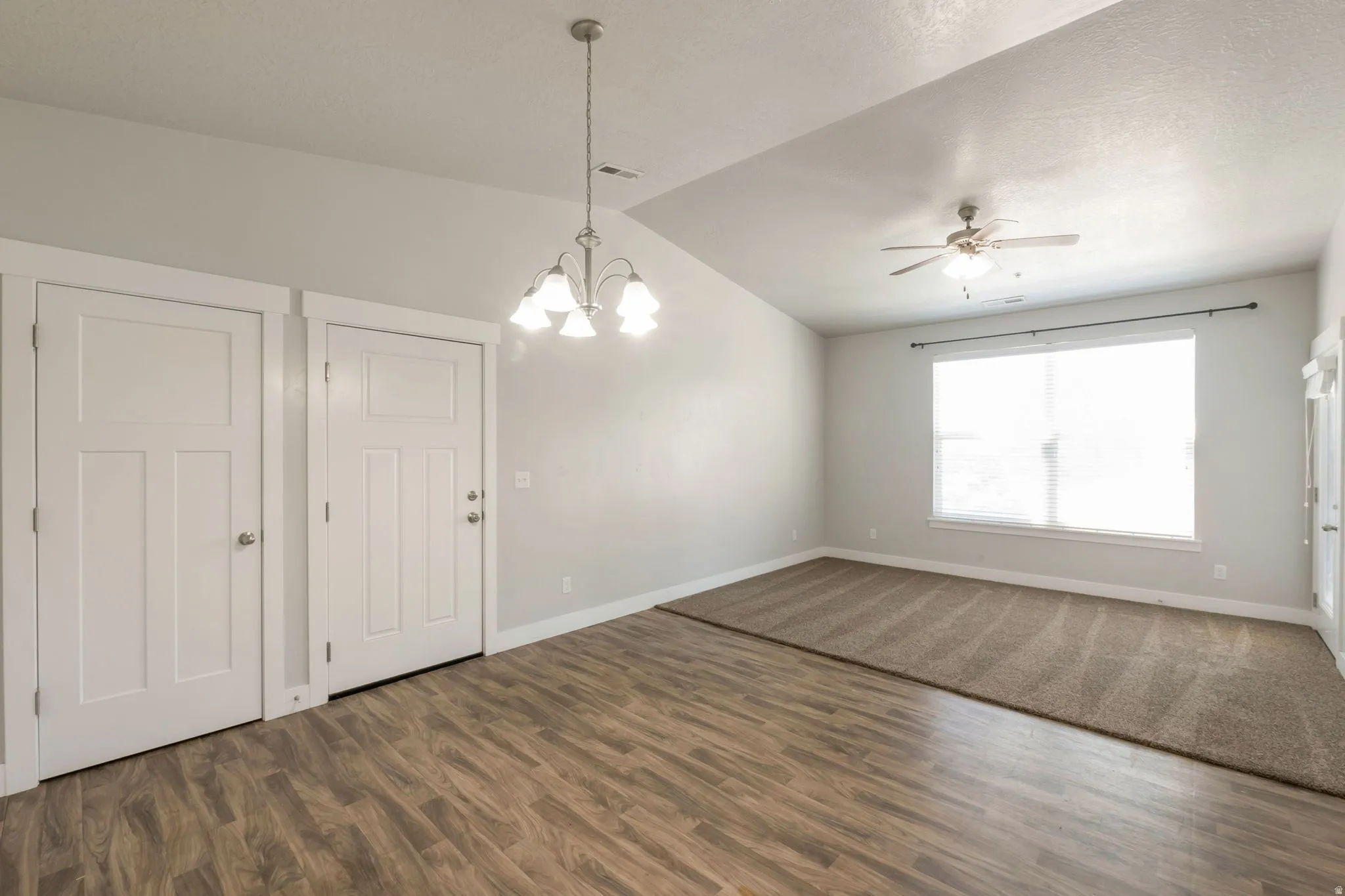 Open concept living area featuring wood-finish flooring, neutral wall tones, and varied ceiling heights