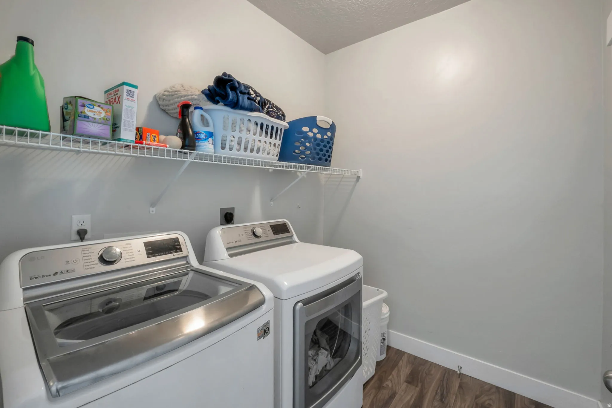 Laundry area with dark wood-style floors, a textured ceiling, and washing machine and dryer