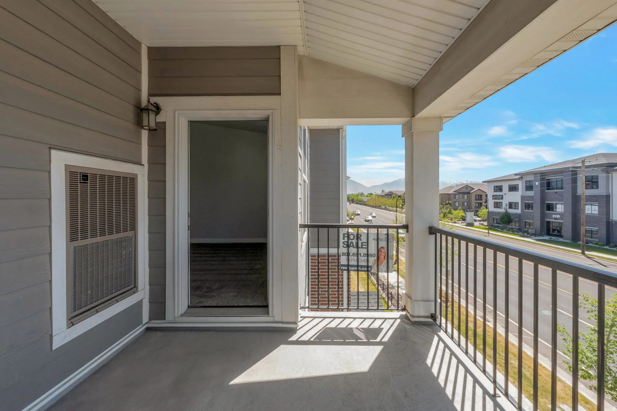 Private balcony with a concrete floor, black metal railing, and white columns