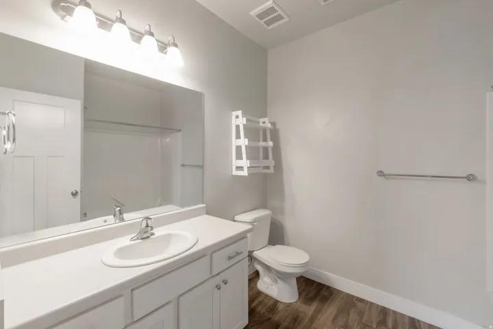 Bathroom featuring a white vanity with an integrated sink, polished chrome faucet, and overhead bar lighting