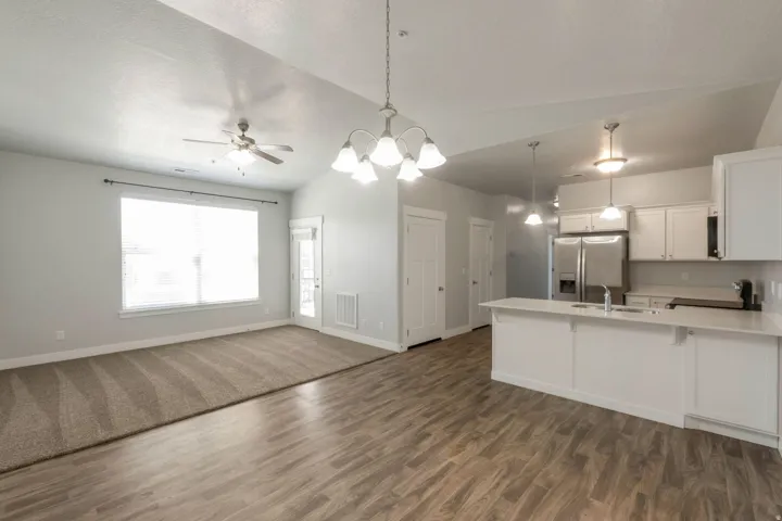 Open-concept living space featuring wood-finish flooring, vaulted ceilings, and a kitchen island with white cabinetry