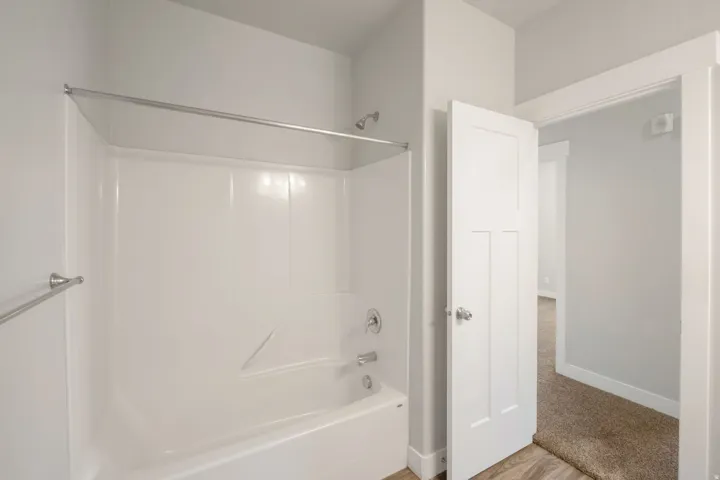 White fiberglass tub and shower combination with a chrome shower head and faucet