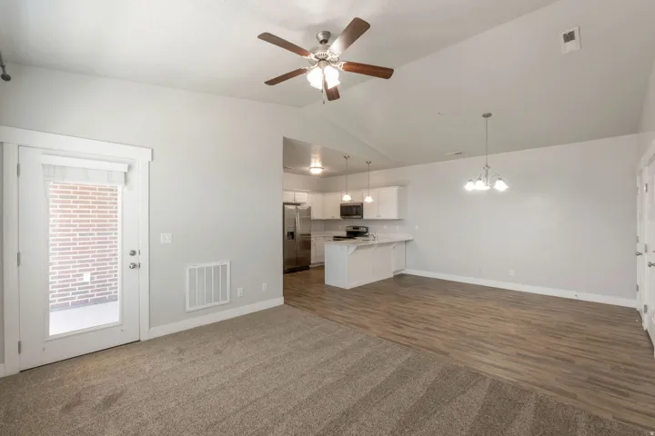Open-concept living area featuring a vaulted ceiling and an integrated ceiling fan